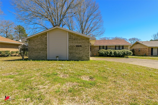 mid-century home featuring driveway, a front lawn, and brick siding