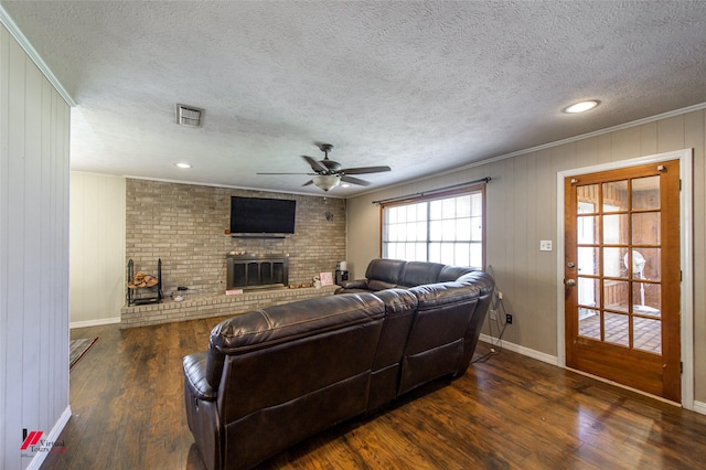 living area with ceiling fan, visible vents, a fireplace, and wood finished floors