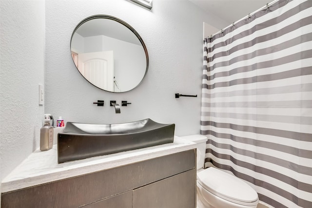 bathroom with a shower with shower curtain, a textured wall, vanity, and toilet