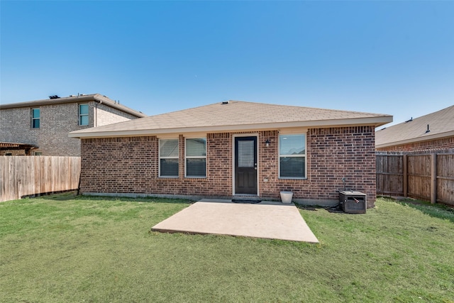 rear view of property featuring brick siding, a lawn, a patio area, and a fenced backyard