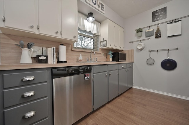 kitchen featuring a sink, light countertops, backsplash, gray cabinets, and dishwasher