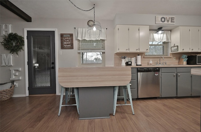 kitchen with light countertops, appliances with stainless steel finishes, wood finished floors, and white cabinetry