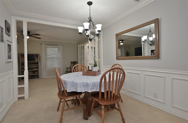 dining room featuring wainscoting, light colored carpet, ornamental molding, a decorative wall, and a notable chandelier