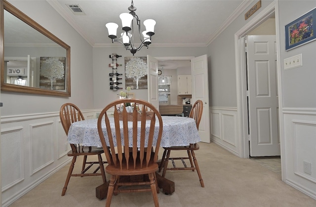 dining room featuring light colored carpet, visible vents, a decorative wall, an inviting chandelier, and ornamental molding