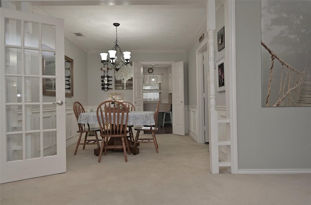 dining space featuring wainscoting, visible vents, ornamental molding, and light colored carpet