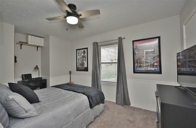 bedroom featuring ceiling fan, a textured ceiling, baseboards, and light colored carpet