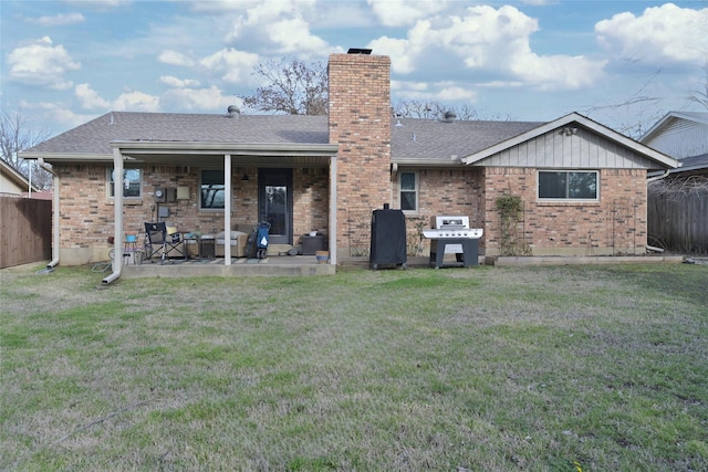 rear view of house featuring roof with shingles, a yard, a chimney, a patio, and fence