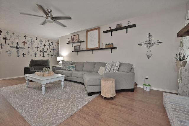 living room with ceiling fan, baseboards, and wood finished floors