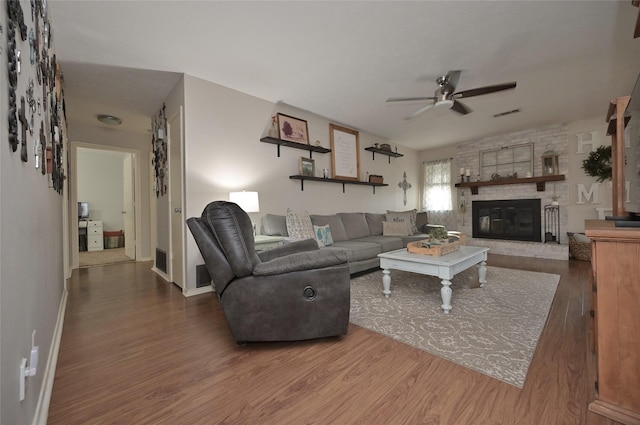 living room featuring a large fireplace, wood finished floors, visible vents, and a ceiling fan