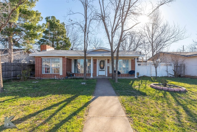 view of front of house featuring a chimney, fence, a front lawn, and brick siding