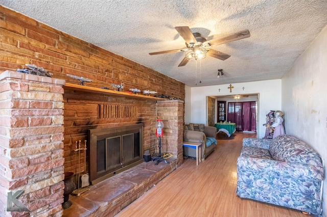 unfurnished living room with a ceiling fan, a fireplace, a textured ceiling, and wood finished floors