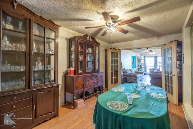 dining area featuring french doors, ceiling fan, light wood-style flooring, and a textured ceiling