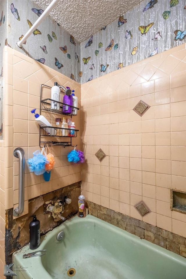 bathroom with wallpapered walls and a bathtub