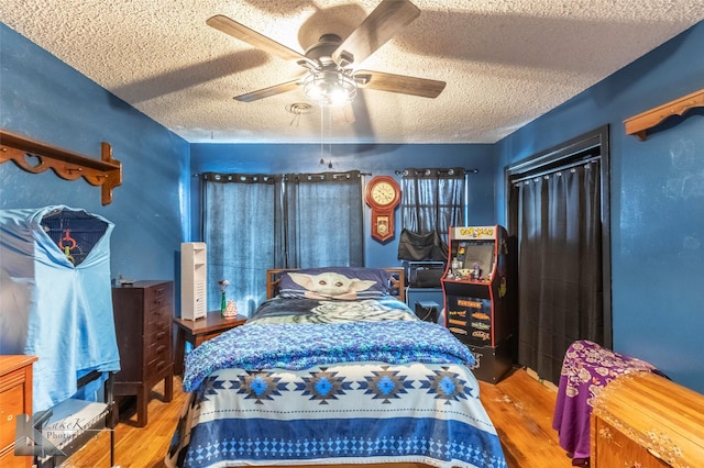 bedroom with a textured ceiling, ceiling fan, and wood finished floors