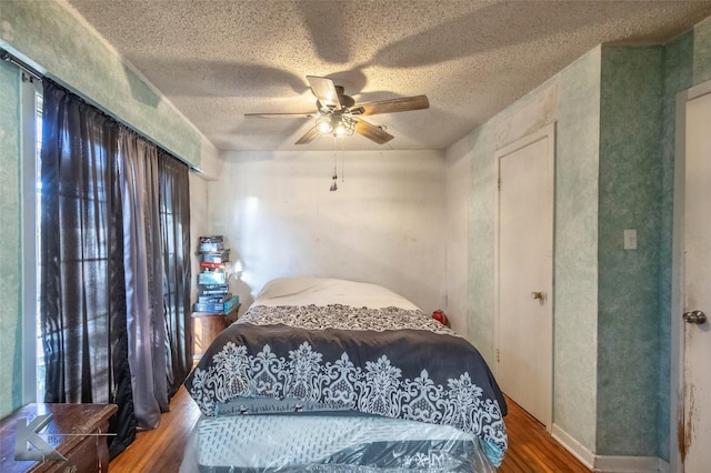 bedroom with a textured ceiling, ceiling fan, and wood finished floors