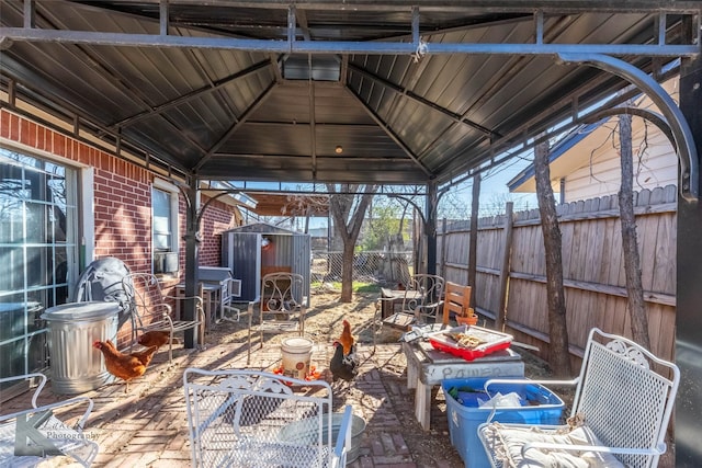 view of patio / terrace with a gazebo, fence, an outdoor structure, and a storage unit