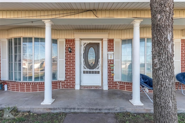 property entrance featuring covered porch and brick siding