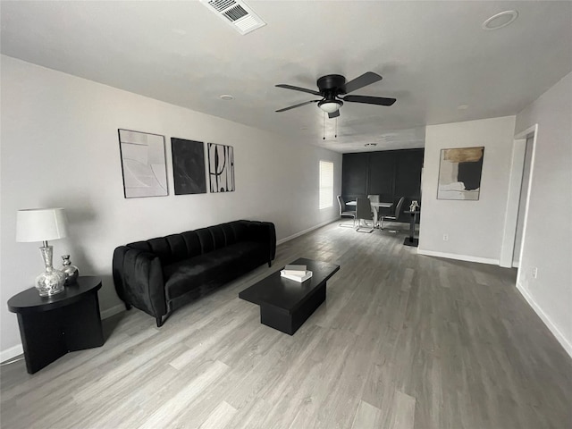 living room featuring wood finished floors, visible vents, and baseboards