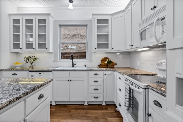 kitchen with white appliances, dark wood finished floors, crown molding, white cabinetry, and a sink