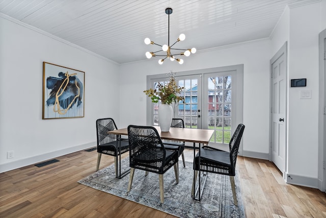 dining area with light wood finished floors, an inviting chandelier, visible vents, and crown molding