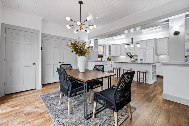 dining room featuring wood ceiling, an inviting chandelier, light wood-style flooring, and ornamental molding