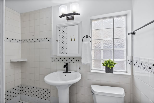 bathroom with toilet, a tile shower, and tile walls