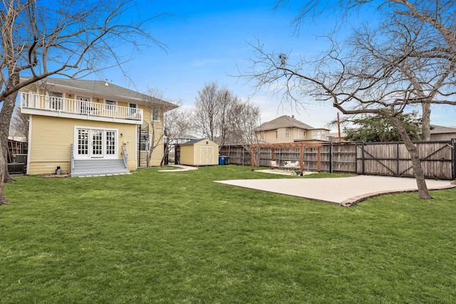 view of yard featuring a patio area, a shed, a fenced backyard, and an outbuilding