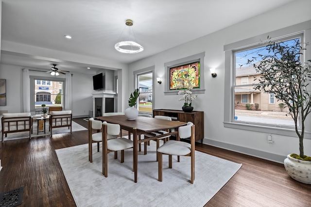 dining room with dark wood-type flooring, a fireplace, recessed lighting, and baseboards