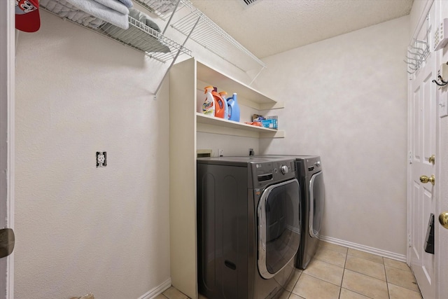 laundry area featuring laundry area, light tile patterned flooring, baseboards, and washing machine and clothes dryer