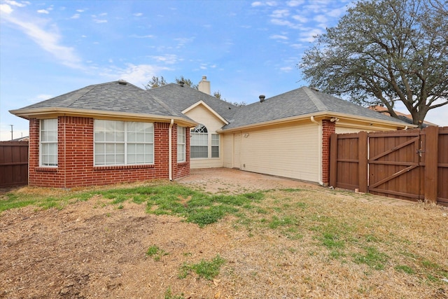 back of property with brick siding, a chimney, a shingled roof, a patio area, and fence