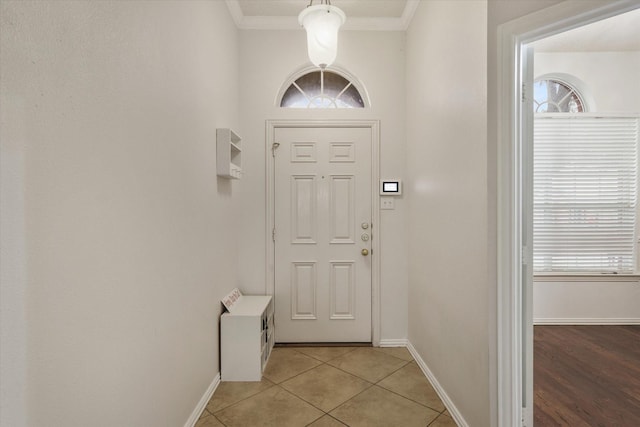 entryway featuring light tile patterned floors, plenty of natural light, ornamental molding, and baseboards