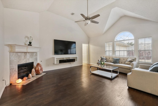 living room with a ceiling fan, high vaulted ceiling, a tiled fireplace, and wood finished floors