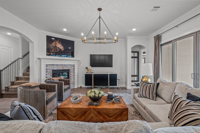 living room with visible vents, stairway, ornamental molding, wood finished floors, and a brick fireplace