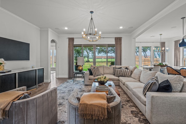 living room with an inviting chandelier, arched walkways, wood finished floors, and ornamental molding