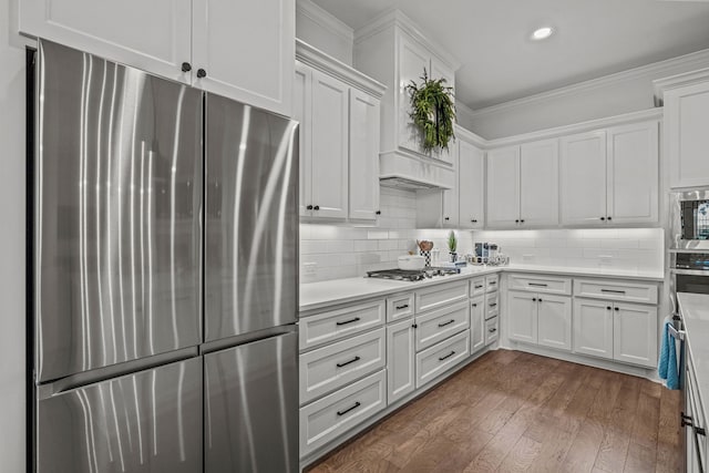 kitchen with stainless steel appliances, white cabinetry, light countertops, dark wood finished floors, and crown molding