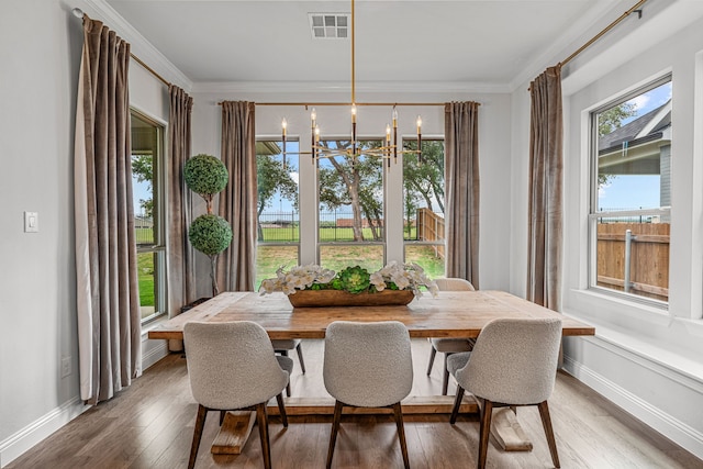 dining area featuring visible vents, baseboards, ornamental molding, hardwood / wood-style floors, and an inviting chandelier