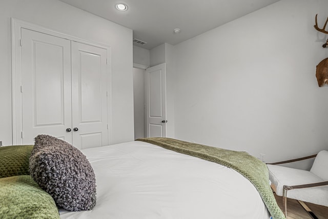 bedroom with a closet, wood finished floors, visible vents, and recessed lighting