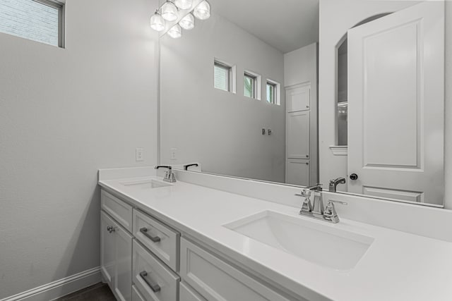 full bath with a sink, baseboards, and double vanity