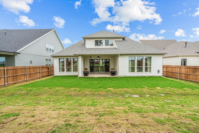 rear view of property with a fenced backyard, a lawn, and roof with shingles