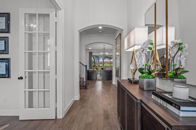 hallway with dark wood-type flooring, arched walkways, ornamental molding, and baseboards