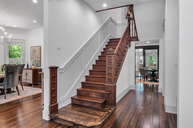 staircase featuring a chandelier, recessed lighting, wood-type flooring, and a decorative wall