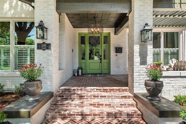 doorway to property with a porch and brick siding