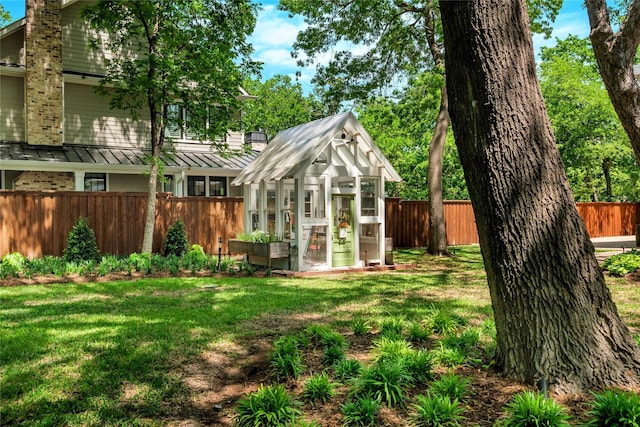 view of yard with a greenhouse, a fenced backyard, and an outdoor structure