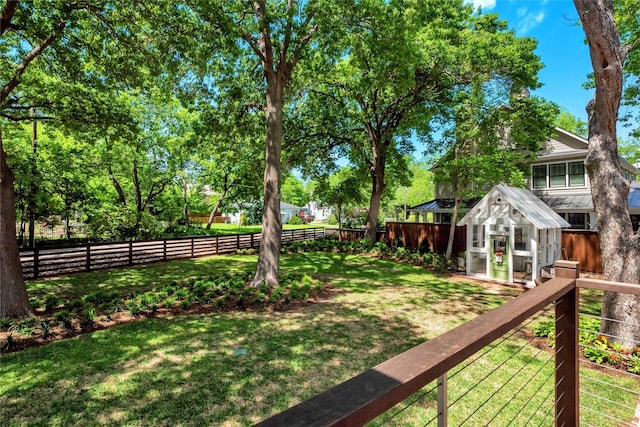 view of yard featuring a fenced backyard, a greenhouse, and an outbuilding