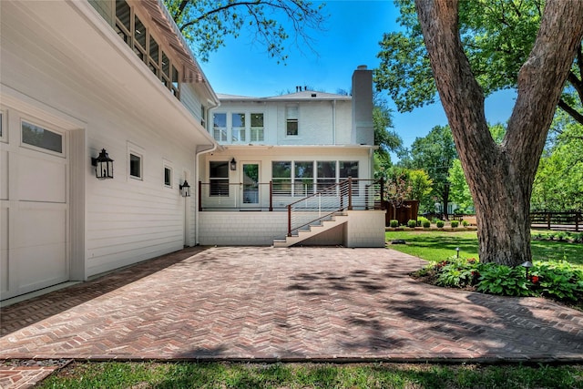 rear view of house featuring a chimney, stairway, and a patio