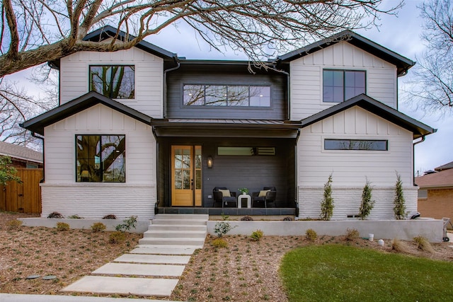 view of front of home with covered porch, board and batten siding, and fence