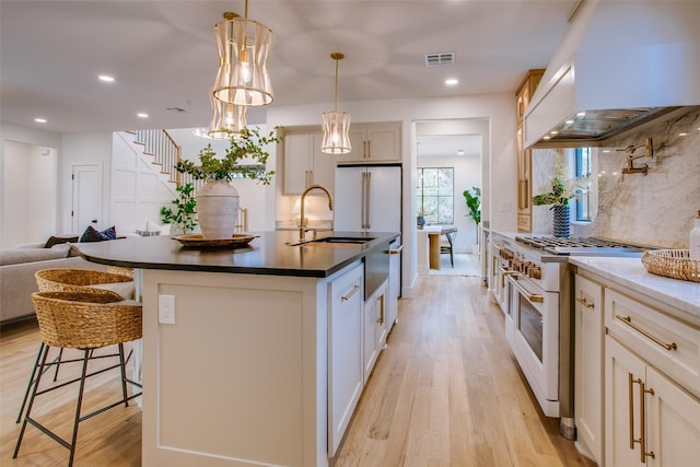 kitchen featuring premium range hood, high end stove, visible vents, and light wood-style floors