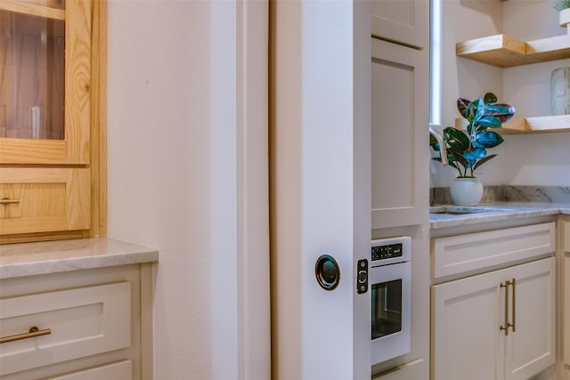 room details with open shelves, a sink, oven, and white cabinets