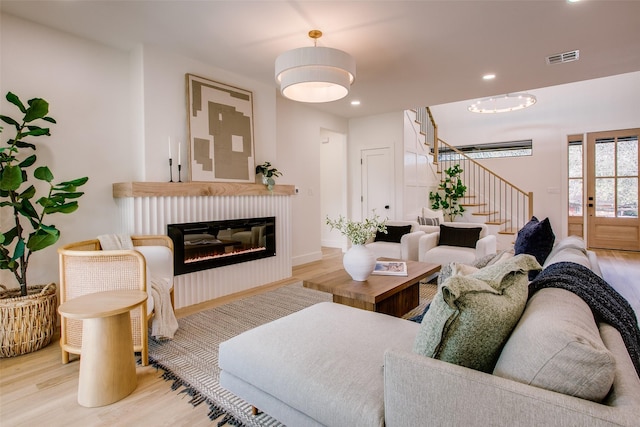 living area with recessed lighting, wood finished floors, visible vents, stairway, and a glass covered fireplace