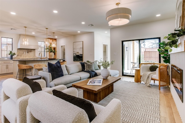 living area with light wood-type flooring, visible vents, and recessed lighting